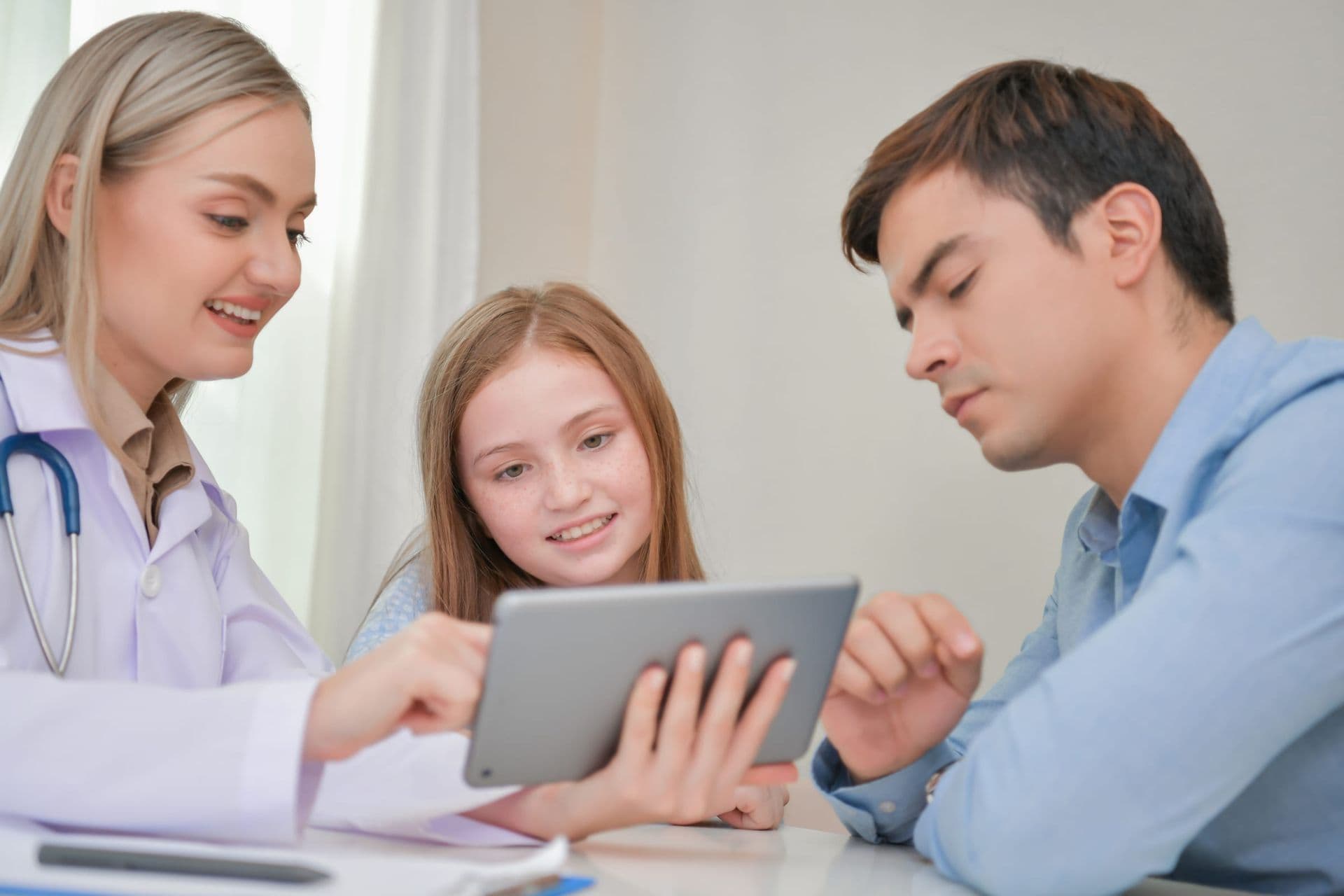 A doctor showing a tablet to a father and his daughter