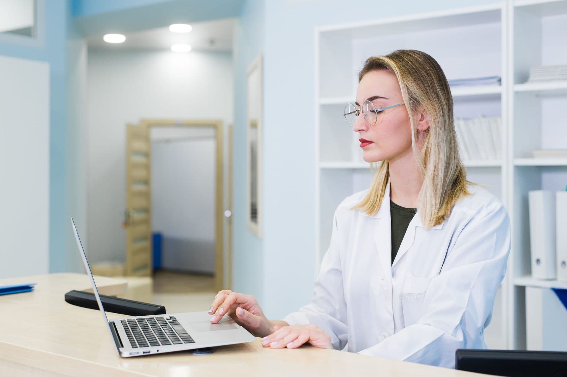A doctor working on a laptop in a bright clinic office